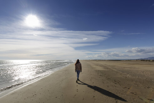 Rückansicht einer jungen Frau, die am Strand entlang spaziert, Tarragona, Katalonien, Spanien - CUF02022