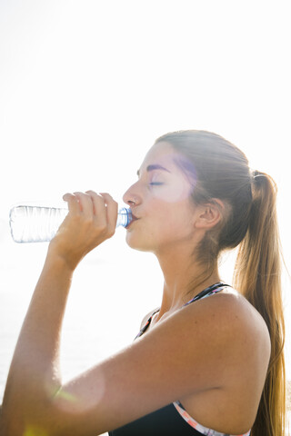 Junge Frau beim Training, trinkt Wasser in Flaschen, lizenzfreies Stockfoto