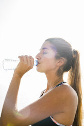 Junge Frau beim Training, trinkt Wasser in Flaschen - CUF02030