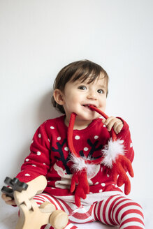 Porträt eines lächelnden kleinen Mädchens mit Rentiergeweih-Stirnband zur Weihnachtszeit - GEMF01936