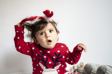 Portrait of disgusted baby girl pulling off reindeer antlers headband - GEMF01943