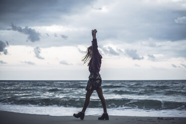 Junge Frau, die in der Abenddämmerung mit erhobenen Armen am Strand spazieren geht, Oblast Odessa, Ukraine - CUF02055