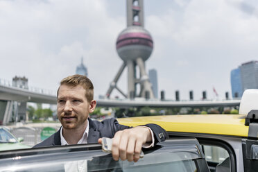 Junger Geschäftsmann beim Aussteigen aus einem gelben Taxi im Finanzzentrum von Shanghai, Shanghai, China - CUF02184