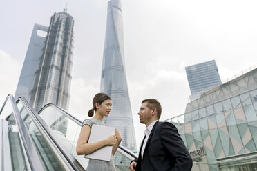 Junger Geschäftsmann und Frau auf der Rolltreppe im Finanzzentrum von Shanghai, Shanghai, China - CUF02194