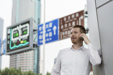 Junger Geschäftsmann telefoniert mit seinem Smartphone in der Stadt, Shanghai, China - CUF02197