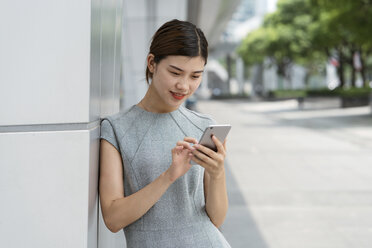Junge Geschäftsfrau mit Smartphone-Touchscreen in der Stadt, Shanghai, China - CUF02198