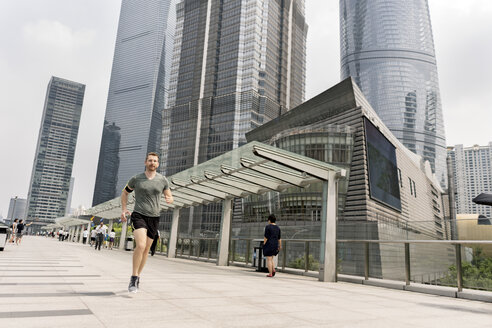 Junger männlicher Läufer beim Laufen im Finanzzentrum von Shanghai, Shanghai, China - CUF02201