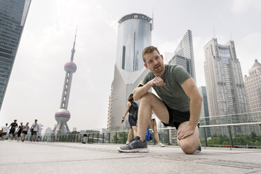 Junger männlicher Läufer macht eine Pause im Finanzzentrum von Shanghai, Shanghai, China - CUF02202