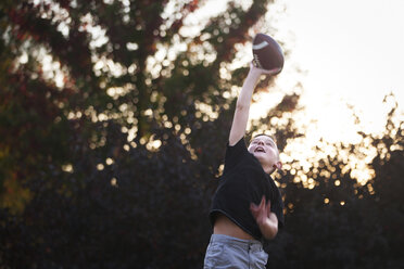 Junge übt American Football im Garten und versucht, den Ball zu fangen - CUF02207