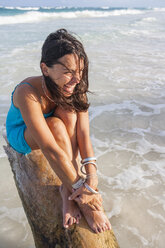 Young woman sitting on log above sea, Tulum, Quintana Roo, Mexico - CUF02222