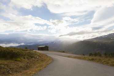 Sunlit rural road in mountain landscape, Jotunheimen National Park, Lom, Oppland, Norway - CUF02407