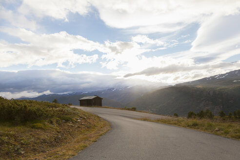 Sonnenbeschienene Landstraße in Berglandschaft, Nationalpark Jotunheimen, Lom, Oppland, Norwegen - CUF02407