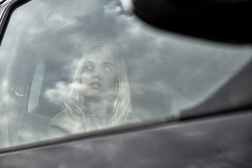 Junge Frau sitzt in einem Auto und schaut aus dem Fenster - MMIF00005