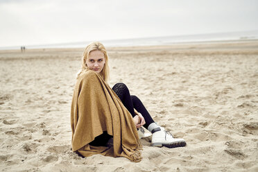 Niederlande, Porträt einer blonden jungen Frau, die am Strand sitzt - MMIF00014