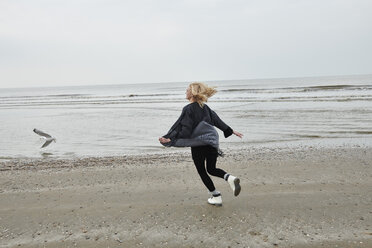 Niederlande, glückliche blonde junge Frau, die am Strand läuft - MMIF00025