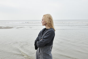 Niederlande, blonde junge Frau steht am Strand und schaut in die Ferne - MMIF00026