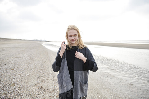 Niederlande, blonde junge Frau mit grauer Jacke am Strand, lizenzfreies Stockfoto