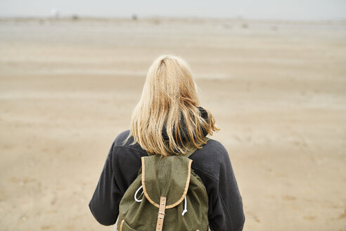 Back view of blond young woman with backpack on the beach - MMIF00039