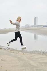 Niederlande, Zandvoort, glückliche junge Frau, die sich am Strand vergnügt - MMIF00043