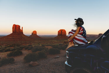 USA, Utah, Woman with United States of America flag enjoying the sunset in Monument Valley - GEMF01949