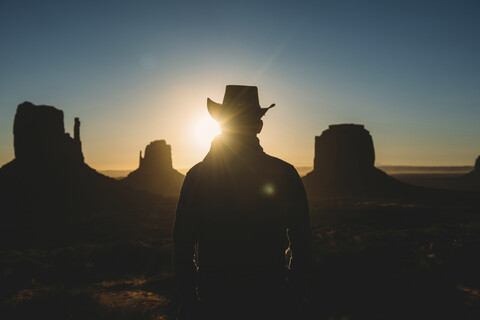 USA, Utah, Mann mit Cowboyhut genießt den Sonnenaufgang im Monument Valley, lizenzfreies Stockfoto