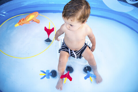 Baby boy sitting in paddling pool stock photo
