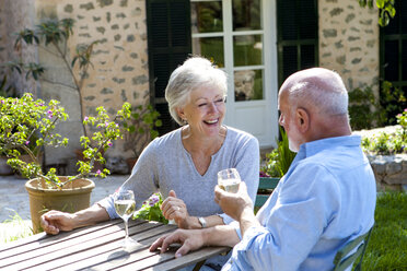 Älteres Paar sitzt im Garten und genießt ein Glas Wein - CUF02472