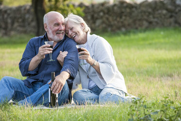 Älteres Paar im Freien, auf einer Decke sitzend, ein Glas Wein genießend - CUF02479