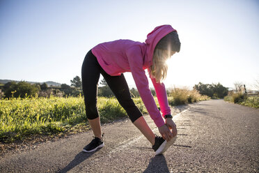 Young woman exercising in rural setting, stretching - CUF02532