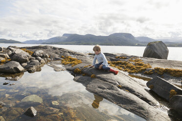 Boy looking at fjord rockpool, Aure, More og Romsdal, Norway - CUF02561