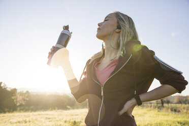 Young woman exercising outdoors, holding water bottle - CUF02569