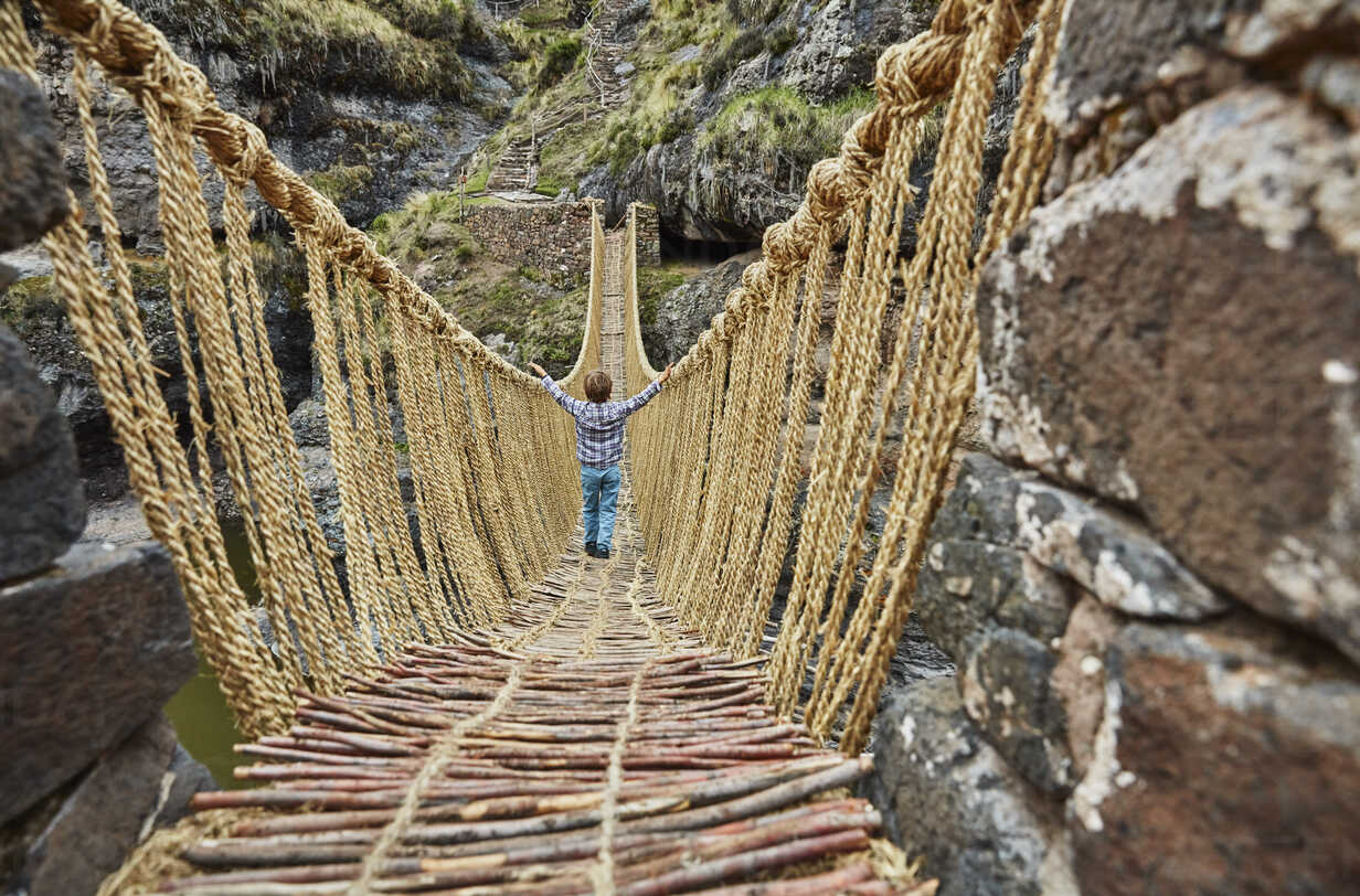 Rear view of boy crossing Inca rope bridge, Huinchiri, Cusco, Peru