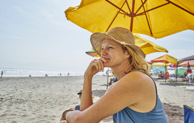 Female tourist sitting under beach umbrella, Camana, Arequipa, Peru - CUF02598