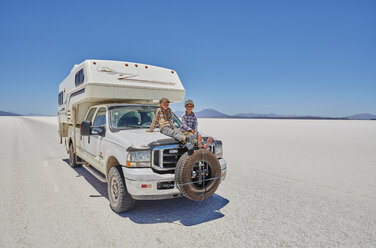 Zwei Jungen sitzen auf einem geparkten Wohnmobil, Salar de Uyuni, Uyuni, Oruro, Bolivien, Südamerika - CUF02603