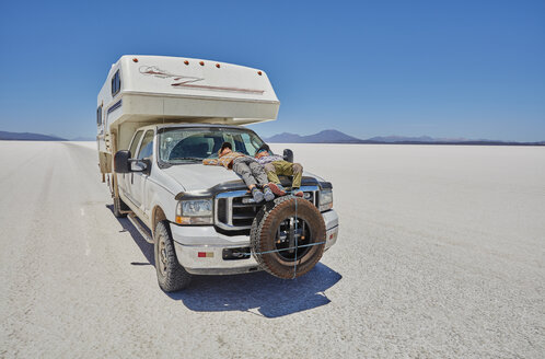 Zwei Jungen entspannen sich auf einem geparkten Wohnmobil, Salar de Uyuni, Uyuni, Oruro, Bolivien, Südamerika - CUF02605