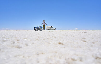 Falschperspektivisches Bild eines Jungen und eines Spielzeuglasters auf einer Salzwiese, der höher steht als das Freizeitfahrzeug im Hintergrund, Salar de Uyuni, Uyuni, Oruro, Bolivien, Südamerika - CUF02606