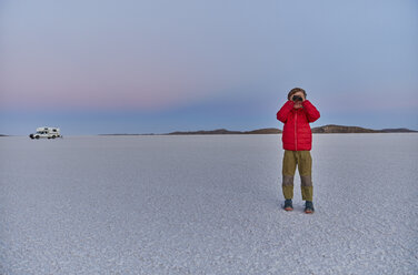 Junge steht auf einer Salzwiese und betrachtet die Aussicht, Wohnmobil im Hintergrund, Salar de Uyuni, Uyuni, Oruro, Bolivien, Südamerika - CUF02613