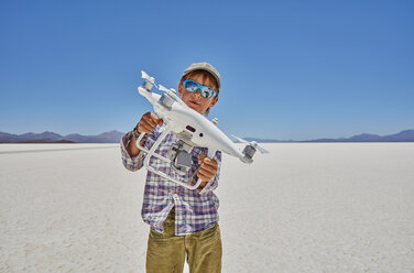 Porträt eines Jungen auf einer Salzwiese, der eine Drohne hält, Salar de Uyuni, Uyuni, Oruro, Bolivien, Südamerika - CUF02618