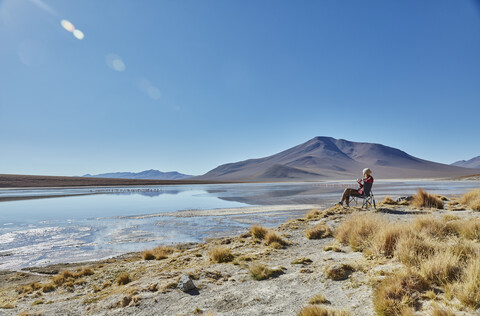 Woman sitting in camping chair, looking at view, Salar de Chalviri, Chalviri, Oruro, Bolivia, South America stock photo