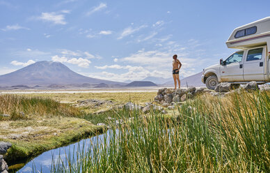 Mature man standing on rock, beside recreational vehicle, looking at view, Salar de Chiguana, Chiguana, Potosi, Bolivia, South America - CUF02633