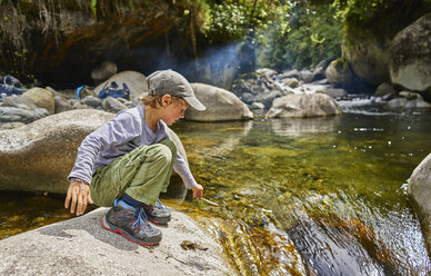 Junge hockt auf einem Felsen neben einem Wasserbecken, Ventilla, La Paz, Bolivien, Südamerika - CUF02647