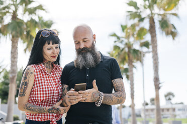 Älteres Hipster-Paar im Park, das auf sein Smartphone schaut, Valencia, Spanien - CUF02688
