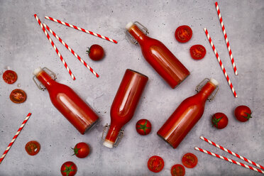 Homemade tomato juice in swing top bottles, straws and tomatoes on grey ground - RTBF01265