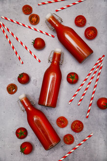 Hausgemachter Tomatensaft in Bügelverschlussflaschen, Strohhalme und Tomaten auf grauem Grund - RTBF01266