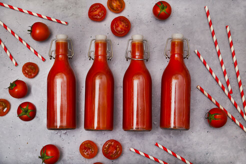 Reihe von vier Bügelverschlussflaschen mit hausgemachtem Tomatensaft, Strohhalmen und Tomaten auf grauem Grund - RTBF01268