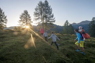 Familienwanderung auf einer Bergwiese bei Sonnenuntergang - HHF05556