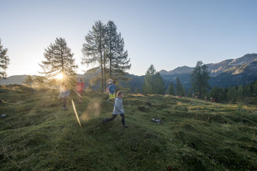 Family hiking in alpine meadow at sunset - HHF05557