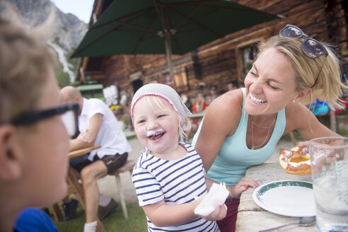 Glückliches kleines Mädchen isst Kuchen mit Familie auf der Almhütte - HHF05561