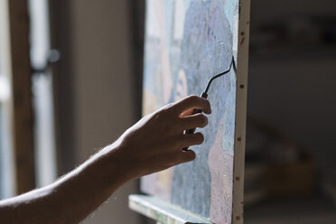 Male artist painting canvas in artists studio, detail of hand - CUF02733