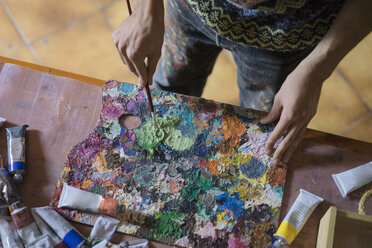 Männlicher Künstler mischt Ölfarbe auf einer Palette in einem Künstleratelier, Mittelteil - CUF02737
